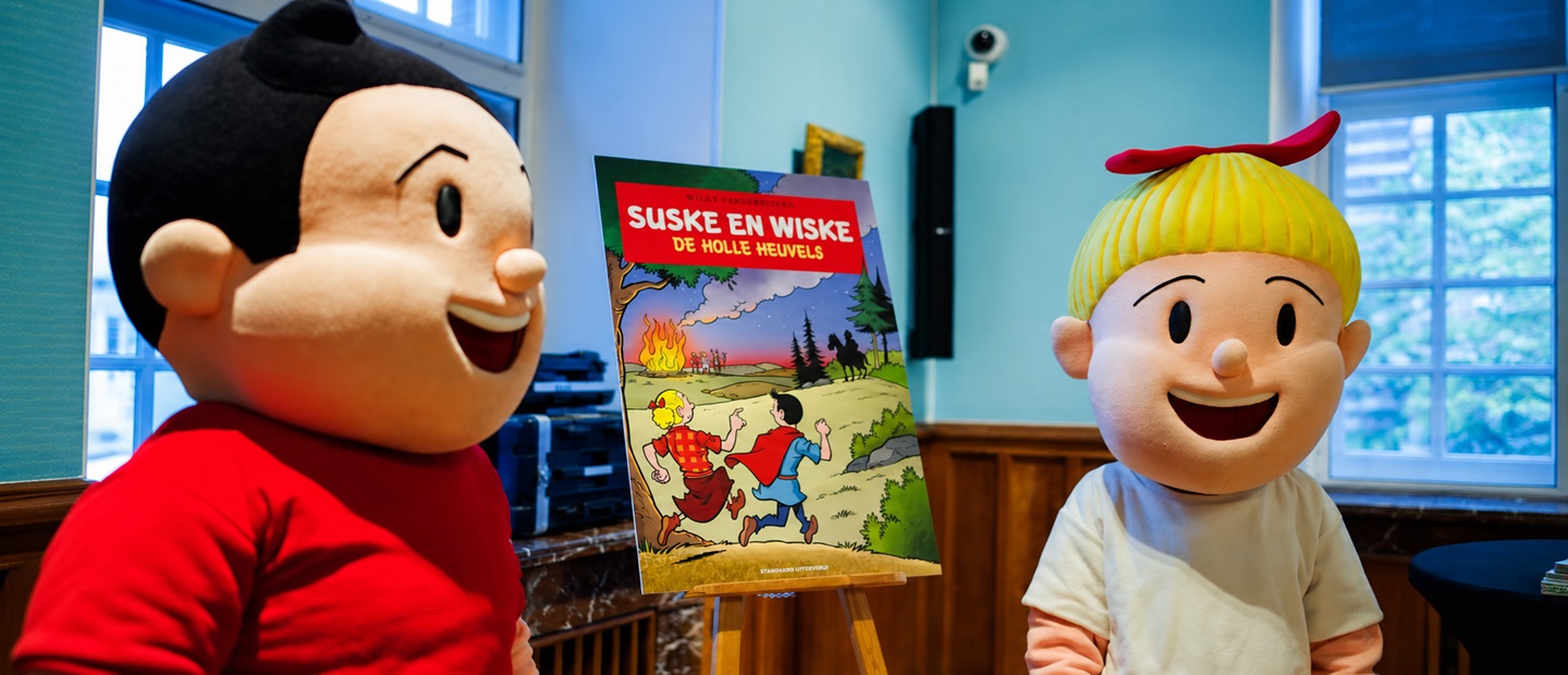 Suske en Wiske staan naast de cover van het speciale stripalbum De holle heuvels, geïnspireerd op het urnenveld op de Boshoverheide in Weert.