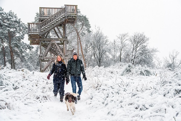 Stelletje wandelt samen met de hond door de sneeuw bij de uitkijktoren 