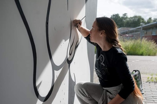 Vrouw is bezig met het maken van een mural op de Hall of Fame in Weert