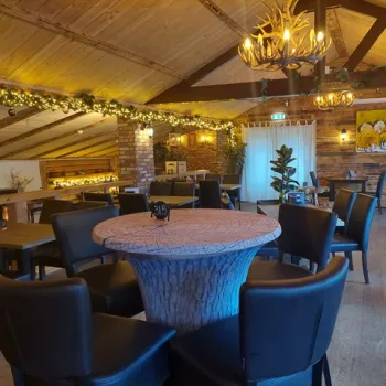 Sfeervol interieur van Boshuis Nieuw Vosseven in Stramproy met houten plafonds, warme verlichting en een boomstamtafel, perfect voor een herfstlunch in bosrijke omgeving.